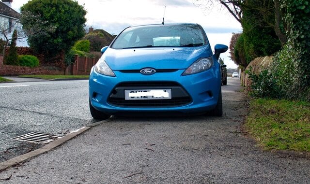 A car parks on the pavement / sidewalk in the UK