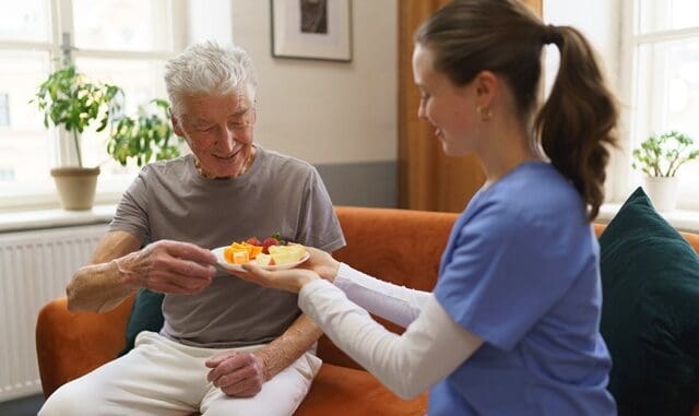 Young nurse prepared fruit snack for senior man.